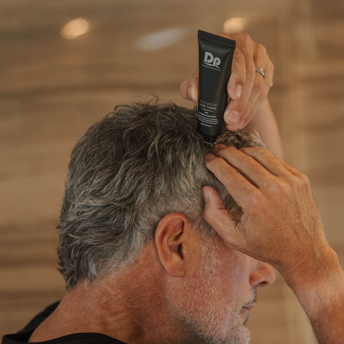 Man applying Exo-Grow hair tonic to scalp