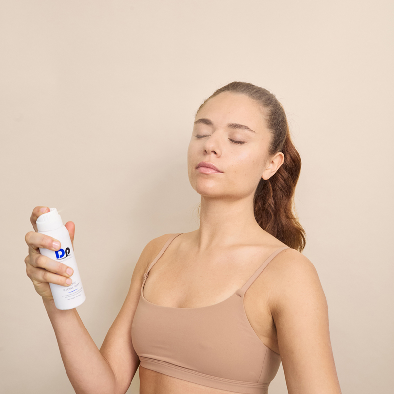 Lady spraying Dp Dermaceuticals Biome Facial Mist on face
