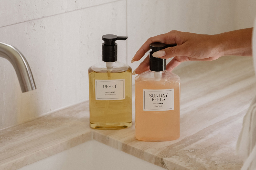 Person touching a hand was bottle on bathroom skink top