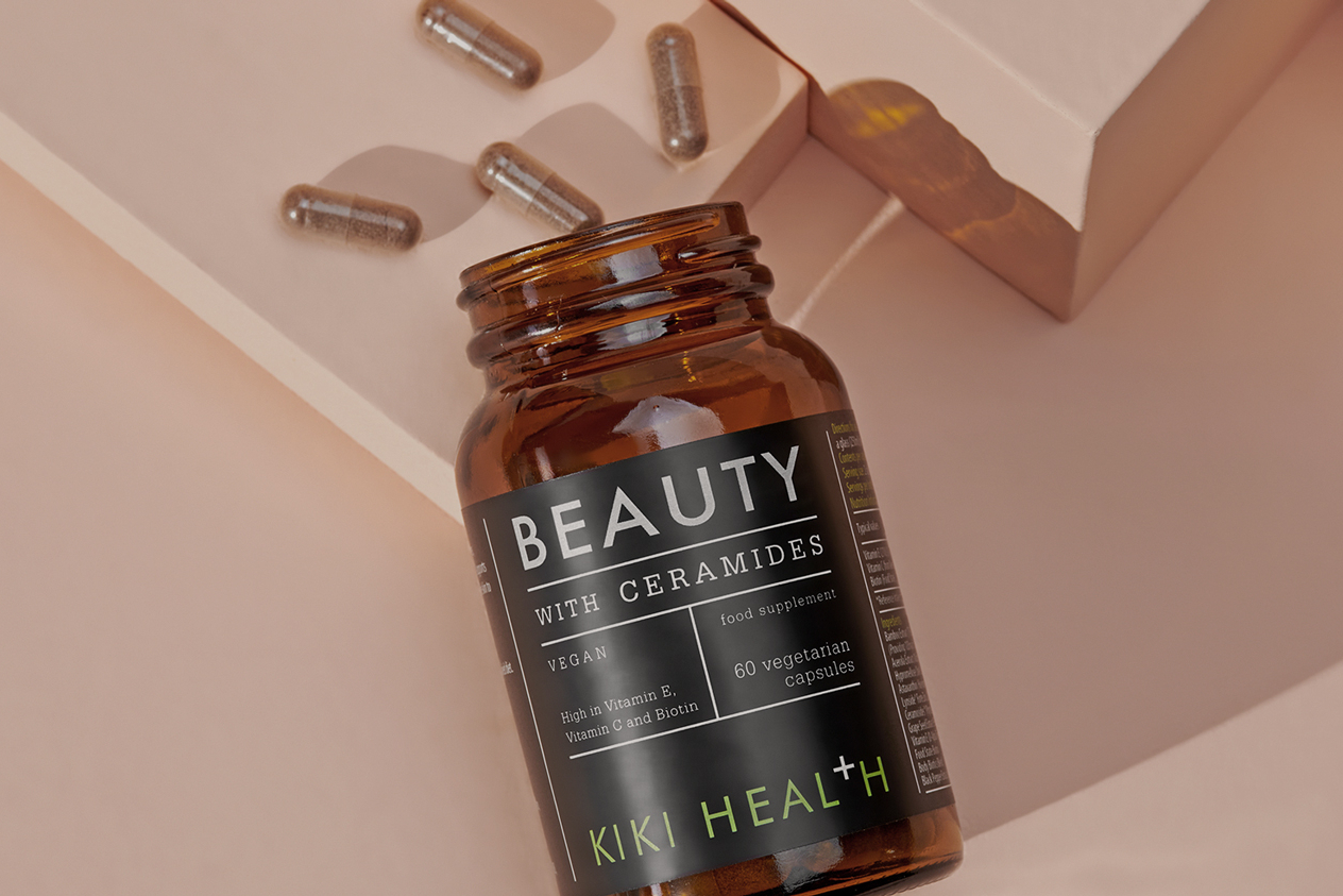 KIKI Health Beauty with Ceramides open with capsules spilling out onto pink desk