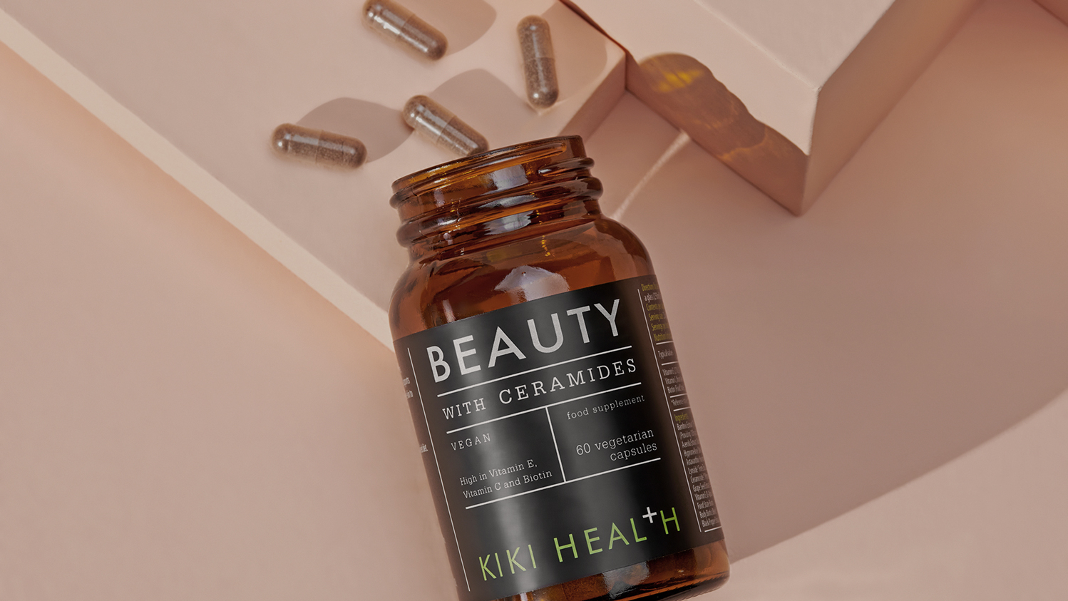 KIKI Health Beauty with Ceramides open with capsules spilling out onto pink desk