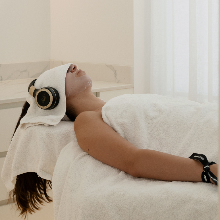 Lady lying on bed receiving mindful facial treatment with headphones listening to meditation