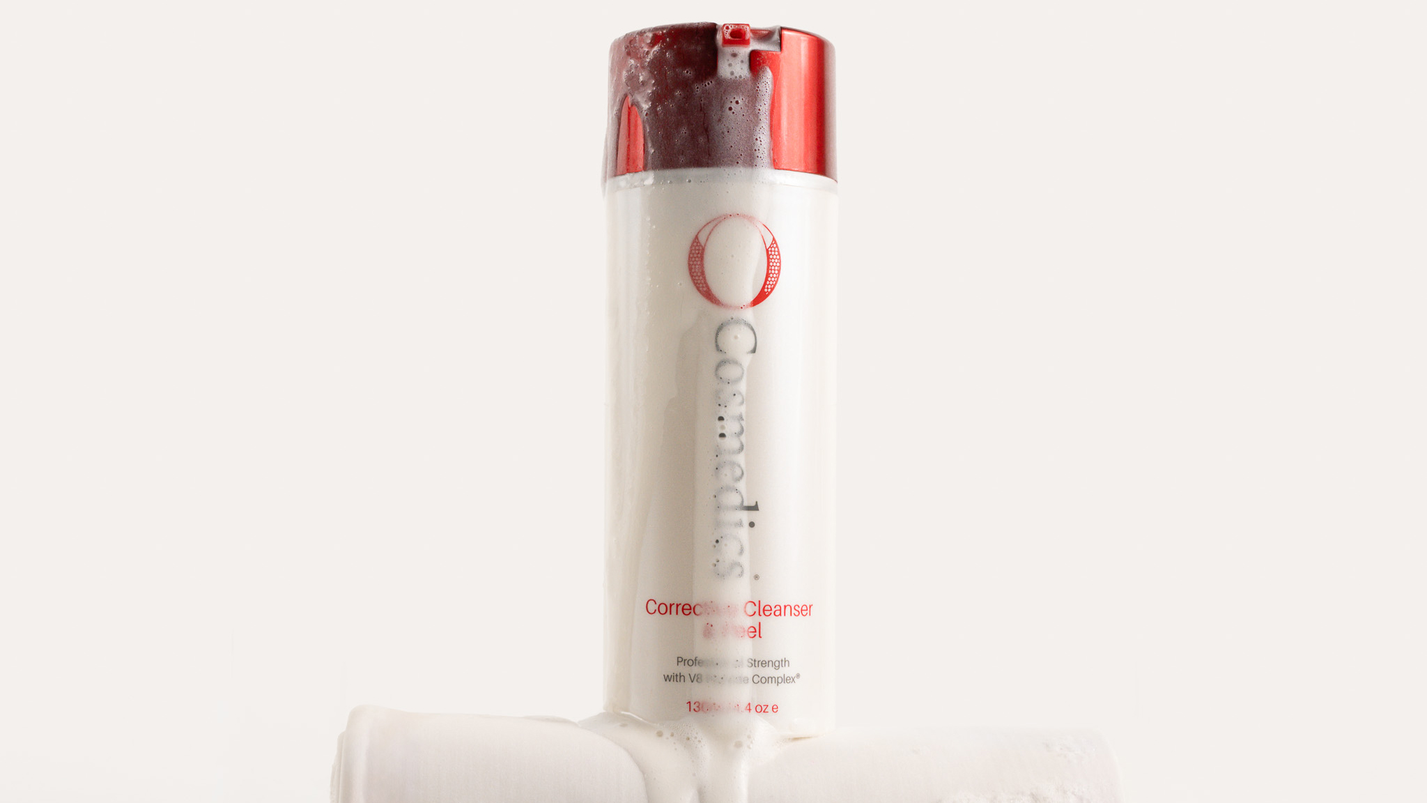 O COSMEDICS Corrective Cleanser & Peel with foam dripping sitting on white cloth
