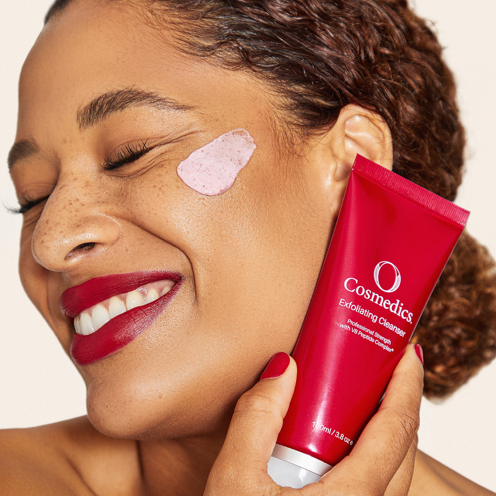 Lady holding O COSMEDICS Exfoliating Cleanser close to face