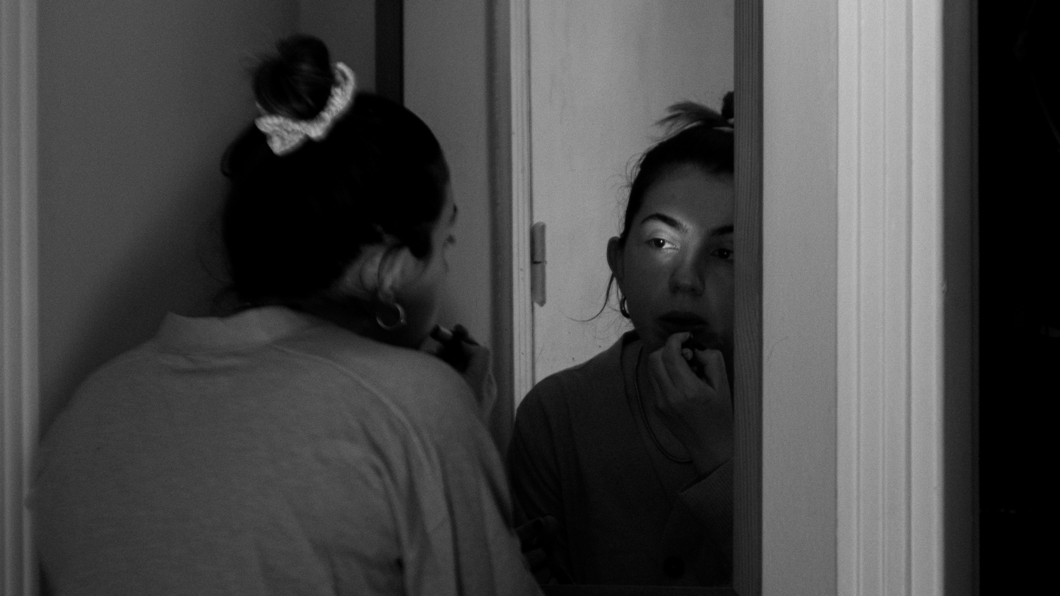 Young woman looking in mirror at skin
