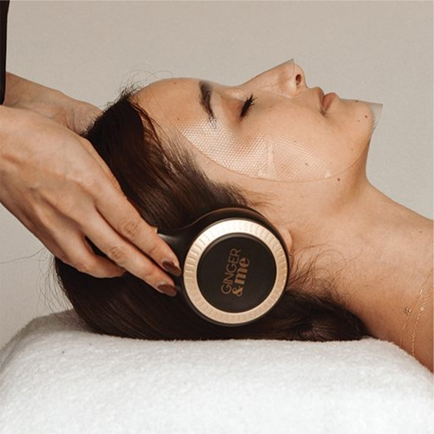 woman with ginger and me headphone and face mask on lyin gon bed