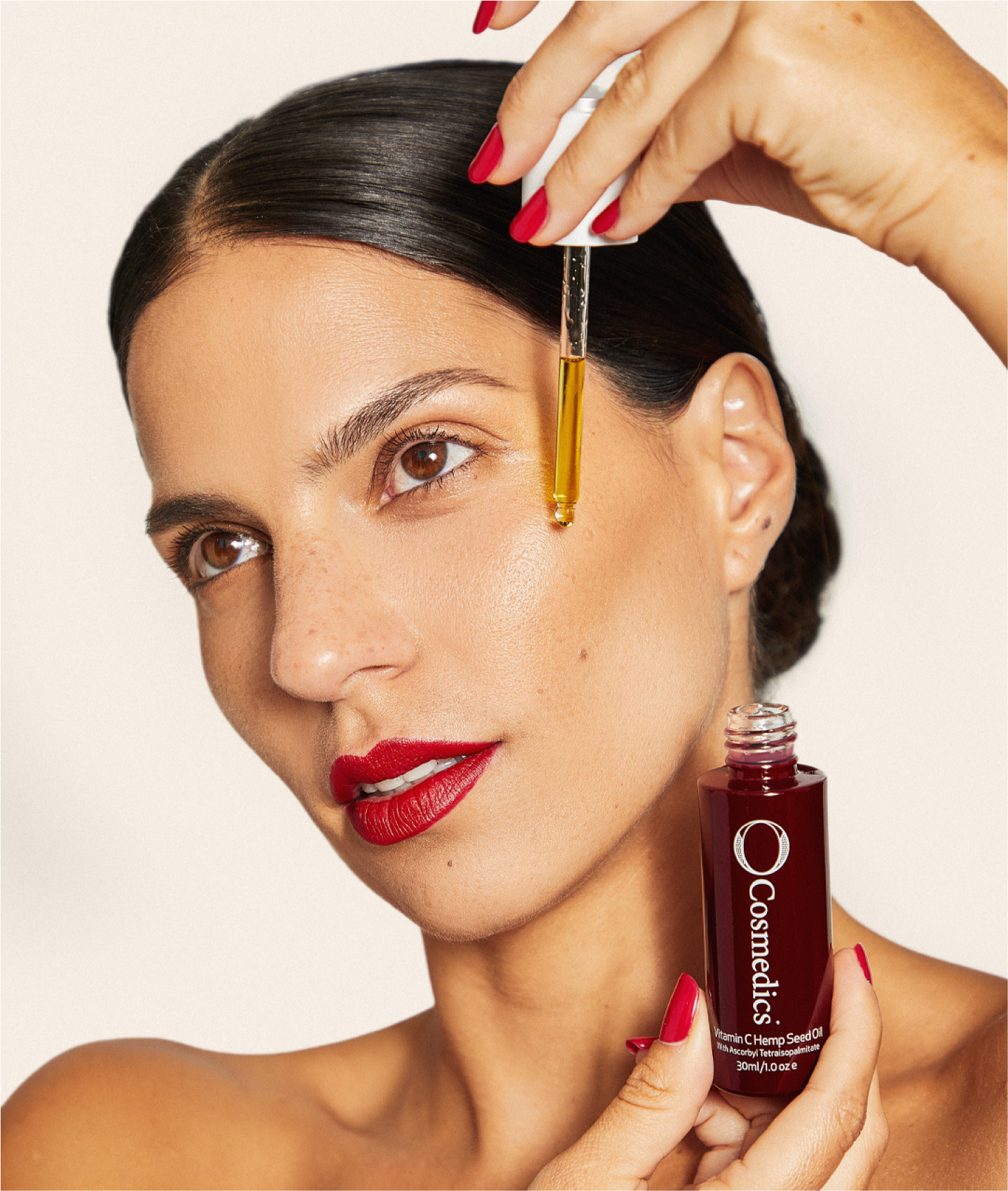 a dark haired woman applying the o cosmedics vitamin c hemp seed oil to her face