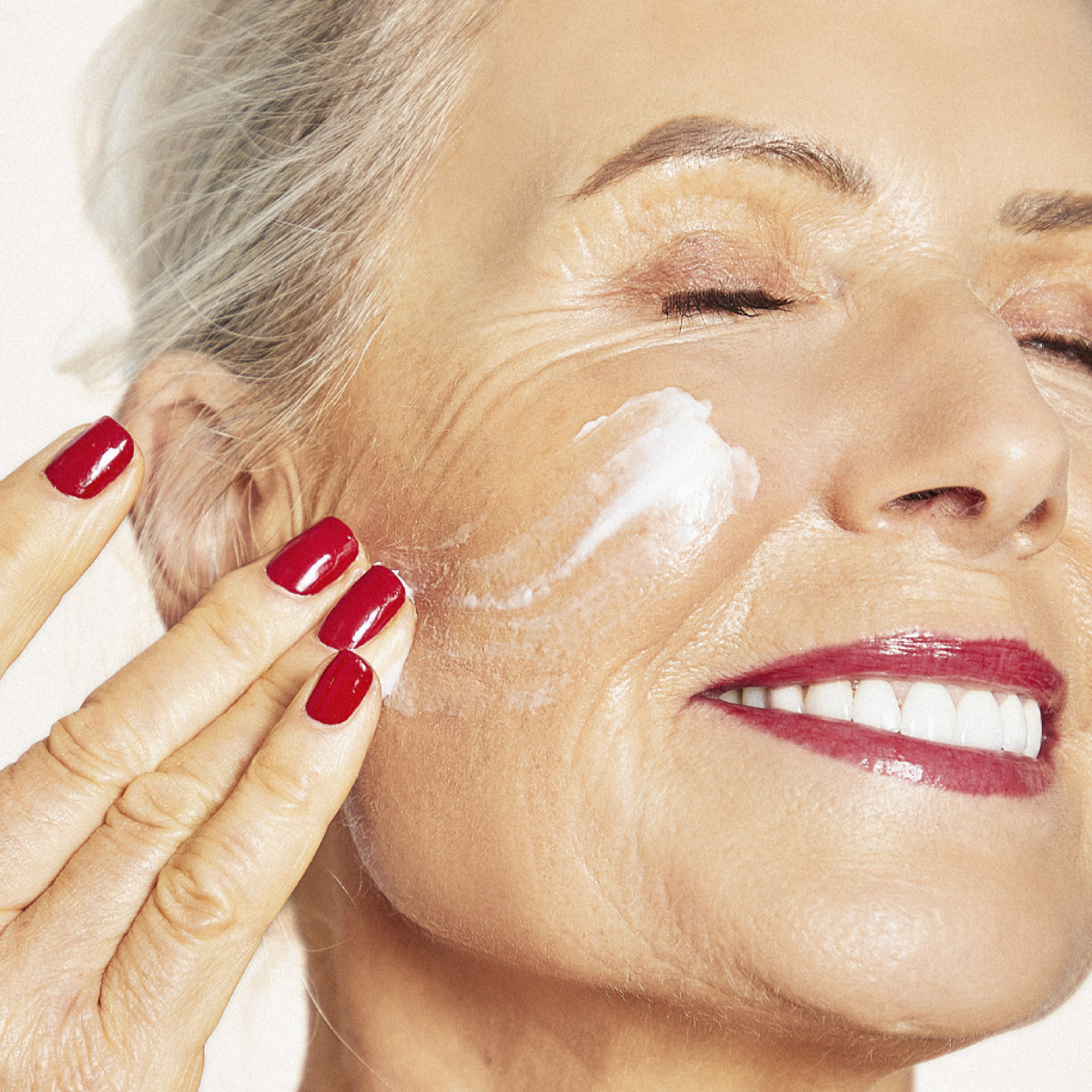 mature woman smiling while applying o cosmedics product on her face