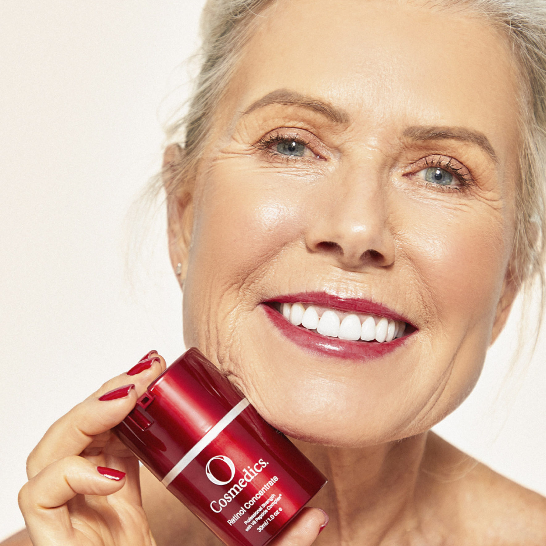 mature woman holding o cosmedics retinol concentrate by her chin