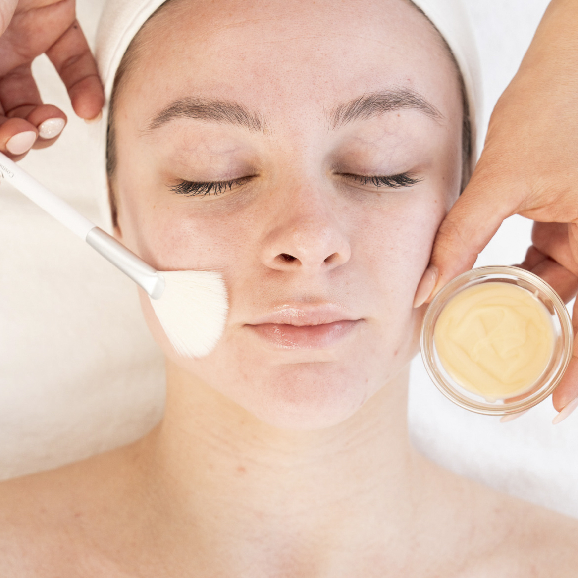 woman laying with eyes closed on treatment bed receiving a peel facial