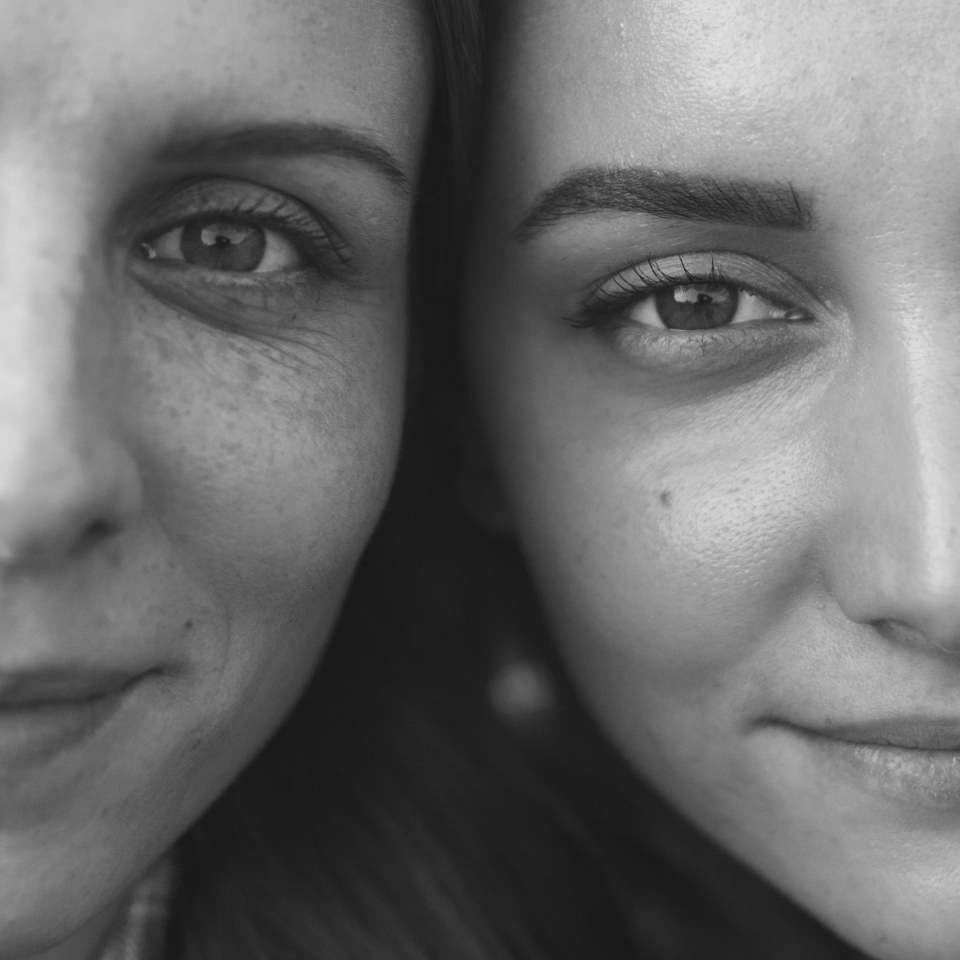black and white image of two women's eyes aligned, smiling with their heads next to each other
